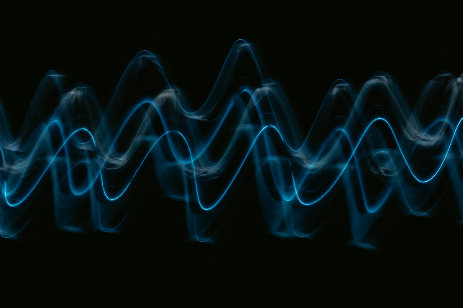 Glowing cyan wave lines stacked across a black background, the shape the waveform ribbon overlay draws across the frame