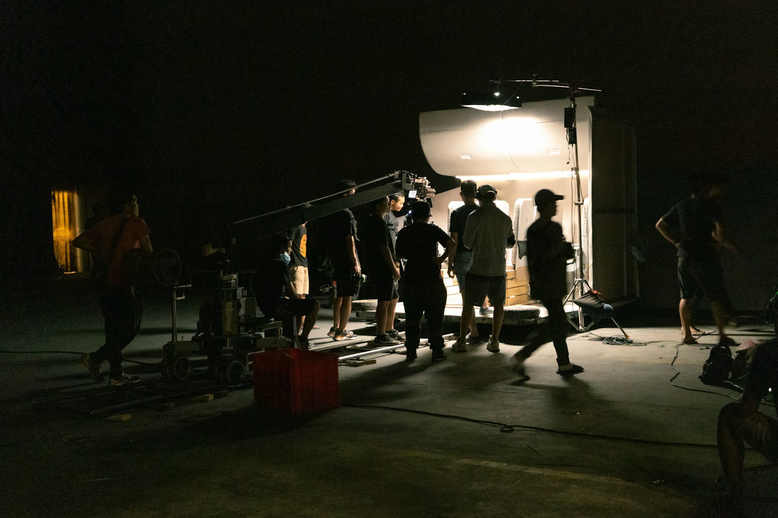 A film crew standing around a camera crane at night beside a lit set, the kind of shoot no browser tool replaces