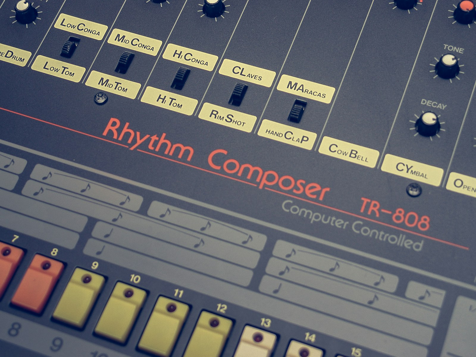 Close up of a Roland TR-808 Rhythm Composer showing its numbered step buttons and instrument row, the drum machine grid dance music was built on