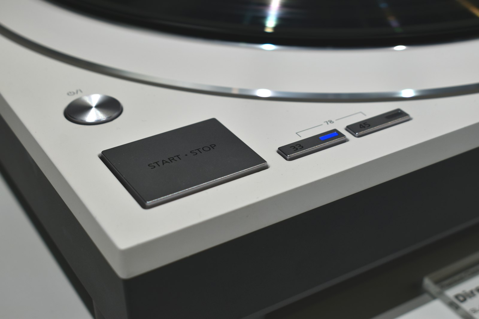 Close up of a turntable control panel showing the start stop button next to the 33, 45 and 78 RPM speed selector with 33 currently lit