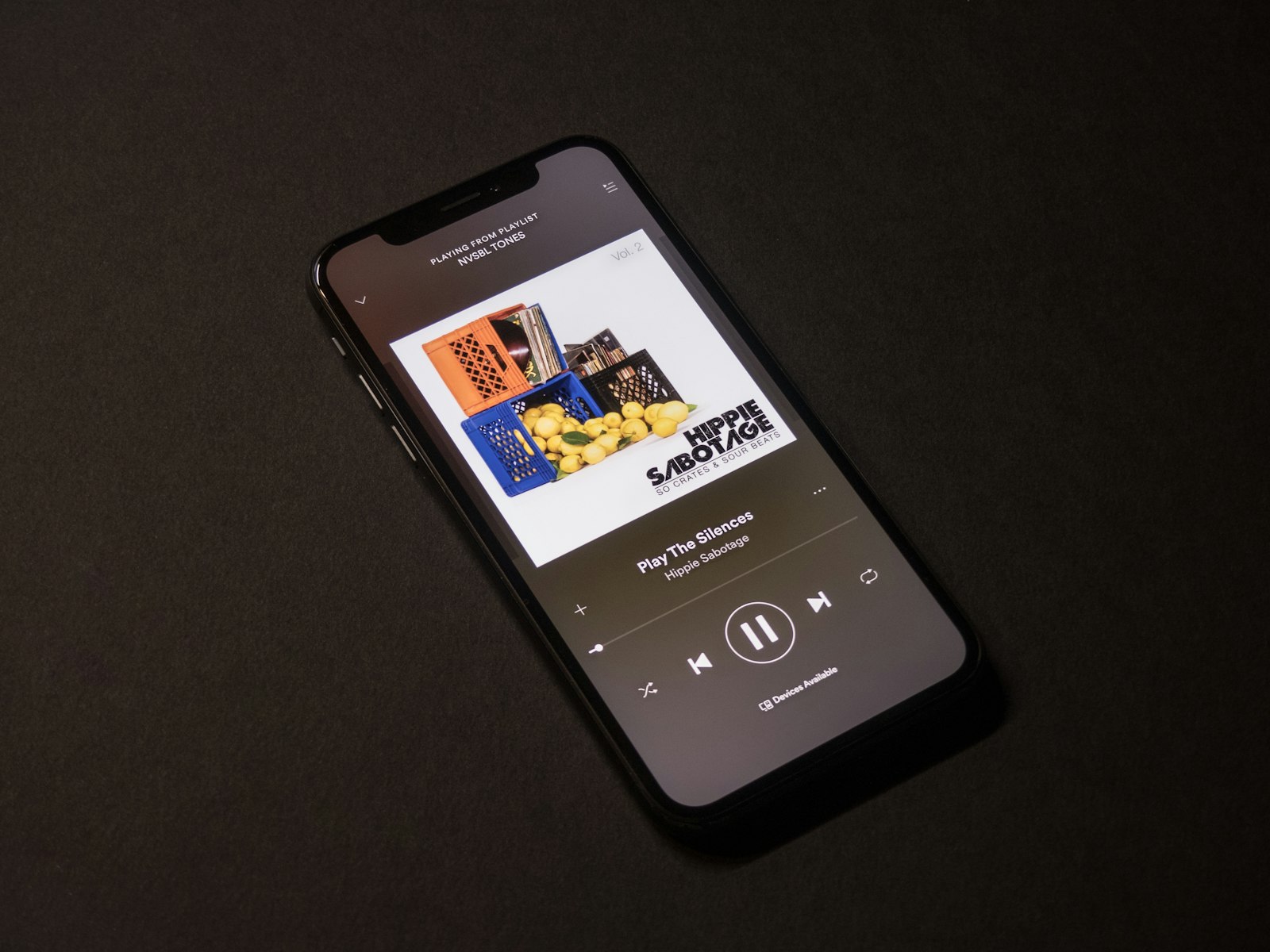 A phone lying on a dark surface showing a streaming app now playing screen with cover art, the exact place a Canvas loop plays