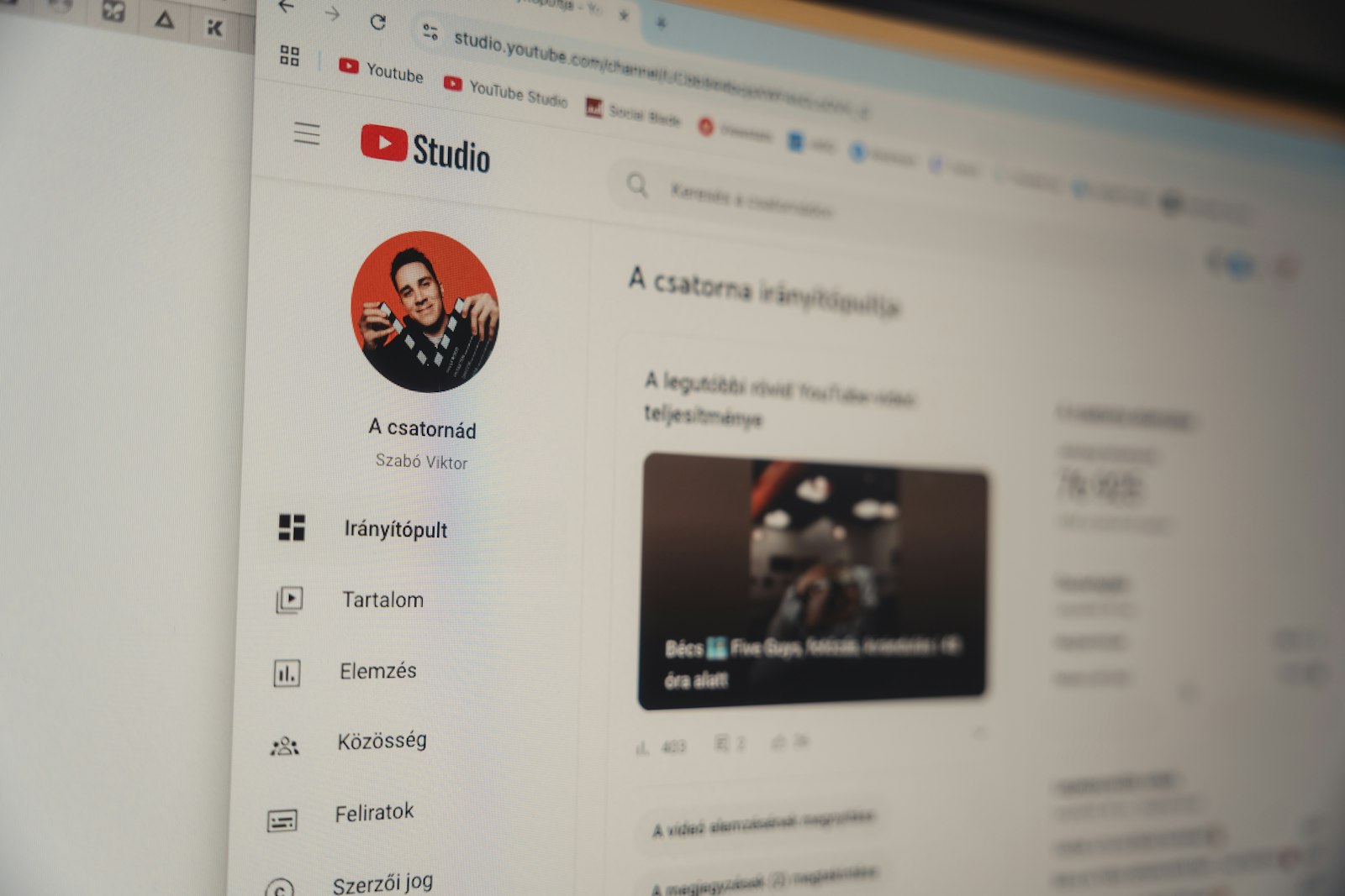 The YouTube Studio channel dashboard open in a browser on an angled monitor, showing the sidebar where uploads, analytics and copyright are managed